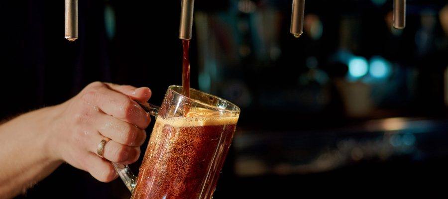 Pouring fresh alcoholic beverage. Batender hand pouring fresh ale beer in glass from beer tap in pub or restaurant.